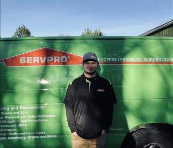 Man with hat standing in front of SERVPRO van