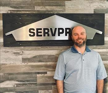 Man Wearing Polo Shirt in front of Servpro sign
