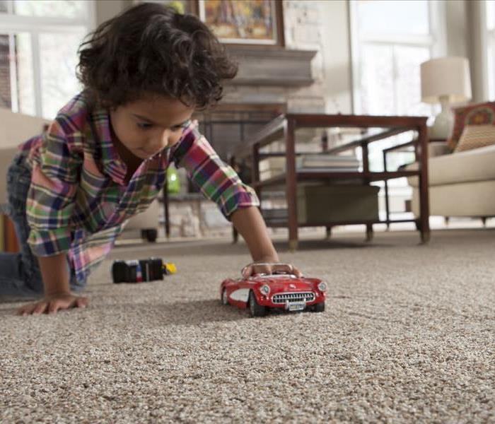 Young Child Playing with a Toy Car on the Floor of the Family Room with Carpet